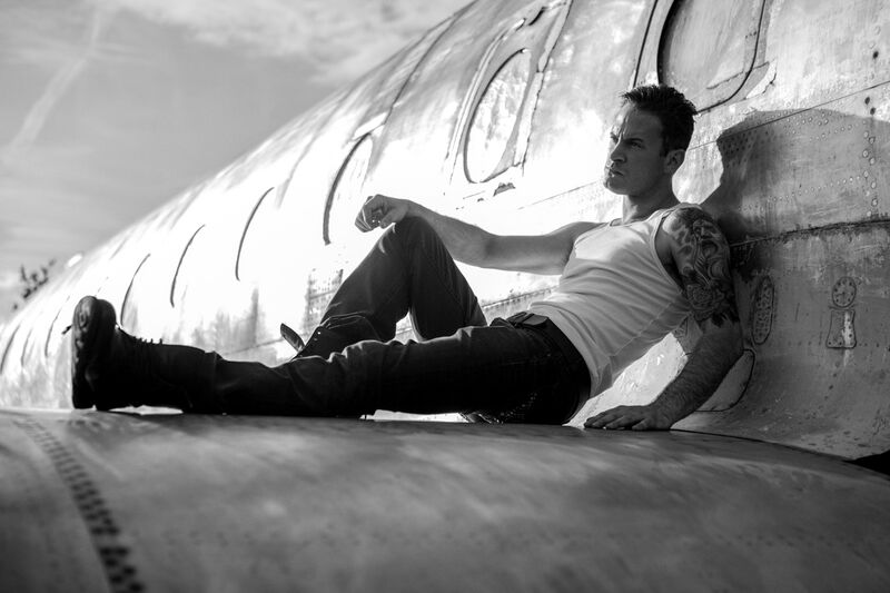 Gary Lucy, editorial portrait, seated on aircraft wing